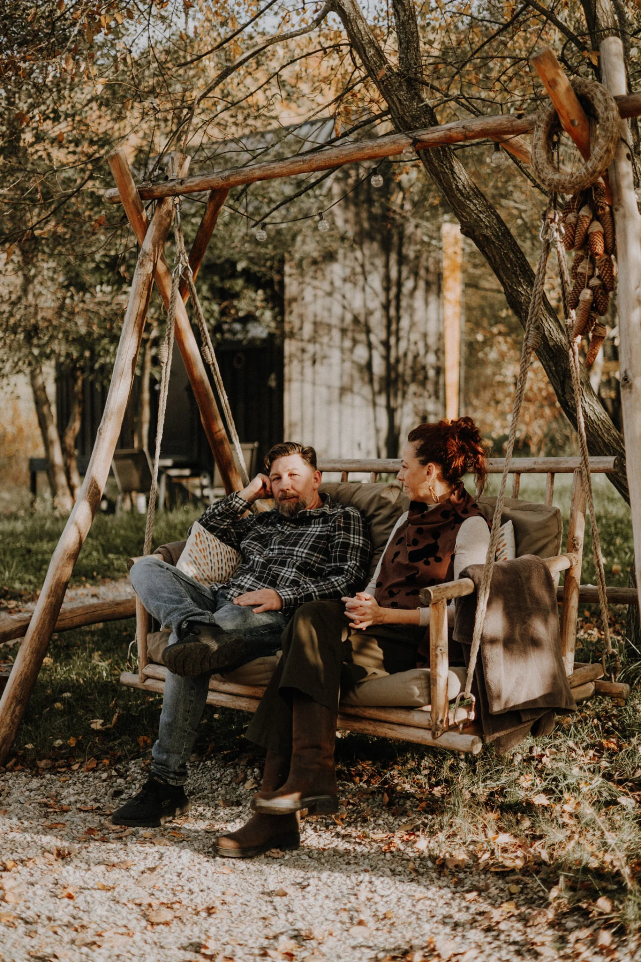 Cuplu relaxându-se în leagănul de lemn, printre frunze de toamnă