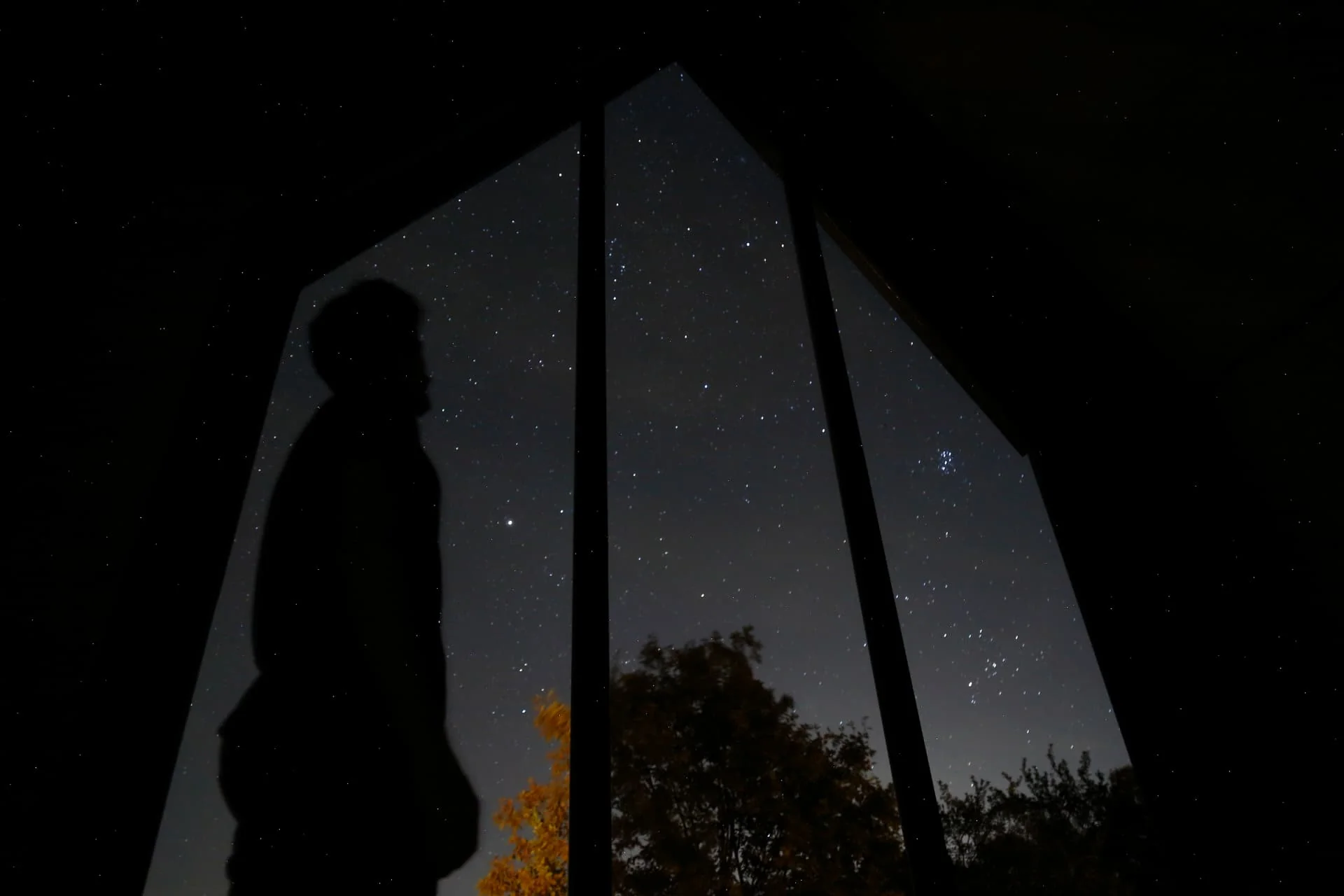 Silueta unui oaspete sub cerul înstelat, lângă portalul bungaloului